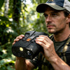 Outdoor explorer holding Minener NightScout Ridge night vision binoculars in a forest, highlighting the handheld design for wildlife and trail observation.